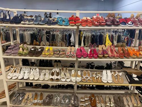 A display of various styles of shoes on shelves, with colorful sandals and flats arranged neatly.