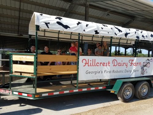 A group of people sitting on a trailer at Hillcrest Dairy Farm, showcasing Georgia's first robotic dairy farm.