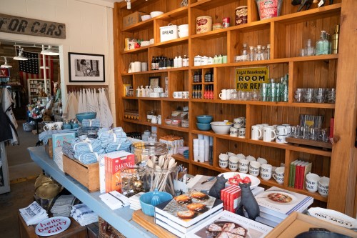 A cozy shop display featuring shelves of kitchenware, cookbooks, and decorative items.