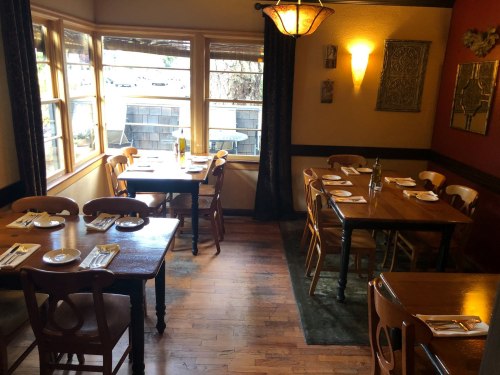 Cozy restaurant interior with wooden tables, chairs, and warm lighting, featuring a welcoming atmosphere.