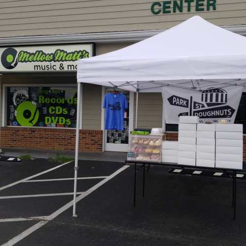 A tent with doughnuts in front of a music store featuring records, CDs, and DVDs.