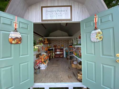 A charming shop interior with green doors, featuring seasonal decorations and gifts on display.
