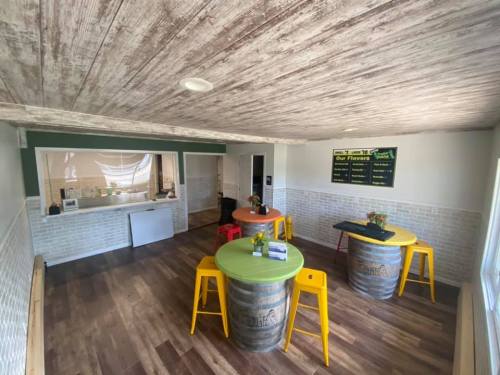 Bright, modern interior of a café with colorful tables, wooden barrels, and a menu board on the wall.