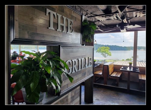 A view of a restaurant interior with a sign reading "The Grille" and a scenic lake visible through the windows.