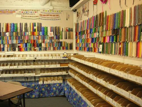 A craft store interior featuring colorful spools of thread and organized boxes of supplies on shelves.