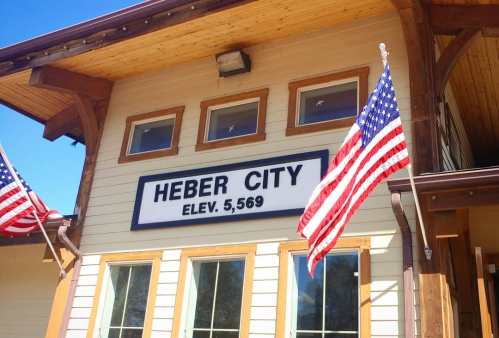 Sign for Heber City with elevation 5,569 feet, featuring American flags on either side of the entrance.
