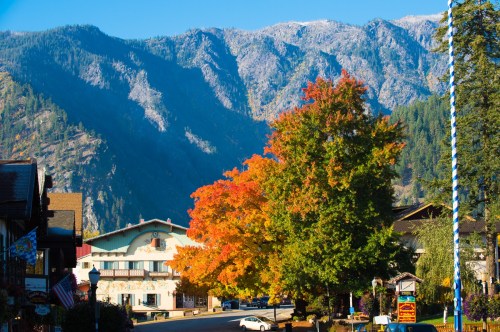 A vibrant autumn scene with colorful trees and mountains in the background, showcasing a charming town.