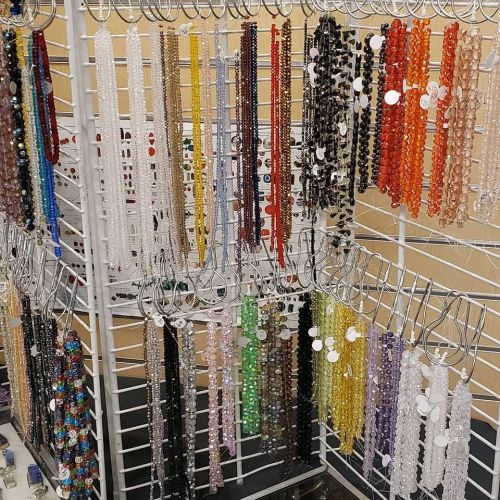 A display of colorful beads hanging on racks, showcasing various shapes and sizes in a craft store.