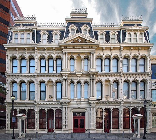Historic building with ornate architecture, featuring multiple windows and a grand entrance, set against a cloudy sky.