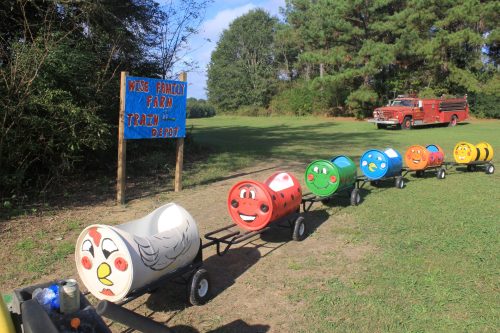Colorful train cars with cartoon faces lined up at a farm, next to a sign for Mike's Family Farm Train Depot.