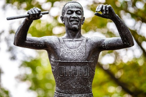 A bronze statue of a joyful athlete in a tank top, raising a baton, with "OHIO" inscribed on the front.