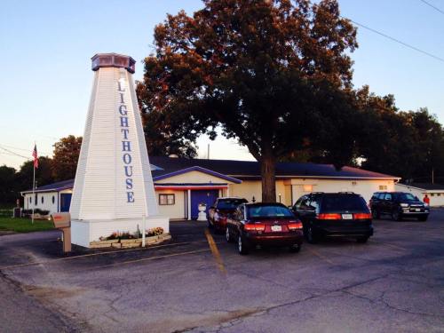 A white lighthouse-shaped building with "Lighthouse" written on it, surrounded by parked cars and trees.