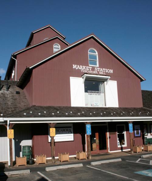 A red barn-style building with "Market Station" sign, featuring large windows and a blue sky in the background.