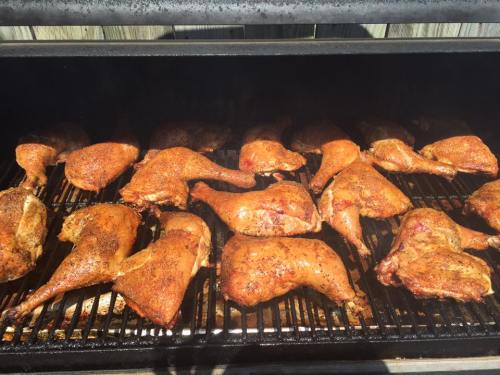 Grilled chicken legs seasoned and cooking on a barbecue grill, with a smoky background.