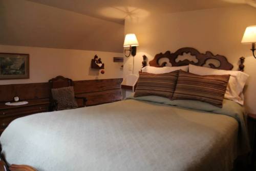 Cozy bedroom with a wooden bed, striped pillows, and soft lighting, featuring a chair and decorative wall art.