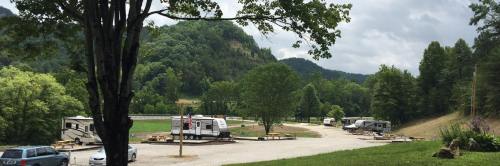 A scenic view of an RV park surrounded by trees and mountains under a cloudy sky.