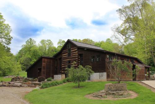 A rustic wooden cabin surrounded by greenery, with a sign reading "Inn at Rainbow" in front.