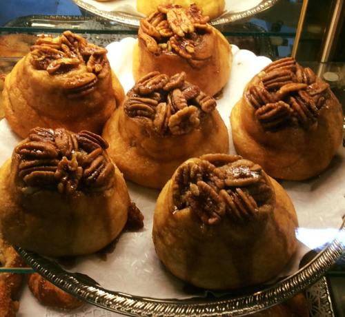 A display of pecan sticky buns topped with nuts, arranged on a silver platter.