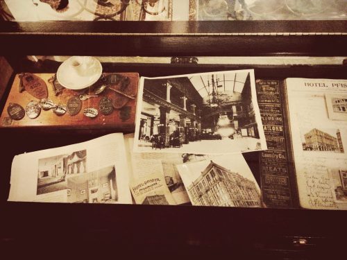 A display case containing vintage photographs, documents, and badges related to a historic hotel.