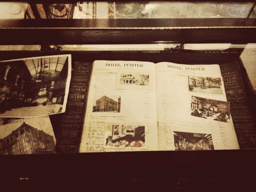 Historic display featuring a scrapbook of Hotel Pfister with photographs and handwritten notes.