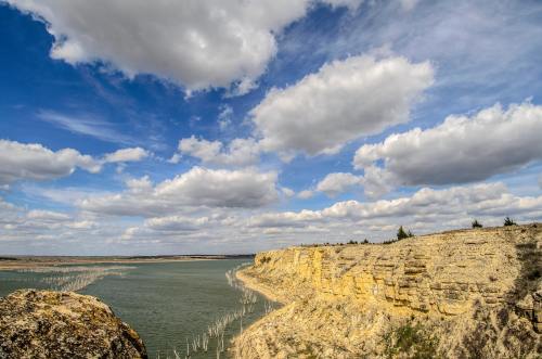 A scenic view of a river winding through cliffs under a partly cloudy sky.