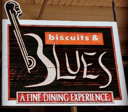 Sign for "Biscuits & Blues" featuring a musical note and text promoting a fine dining experience.