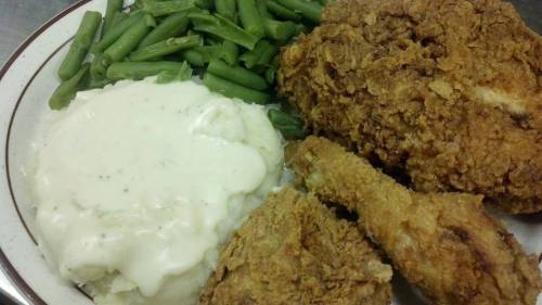 A plate of fried chicken, creamy mashed potatoes with gravy, and steamed green beans.