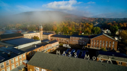 Aerial view of MASS MoCA with autumn foliage and a misty mountain backdrop.