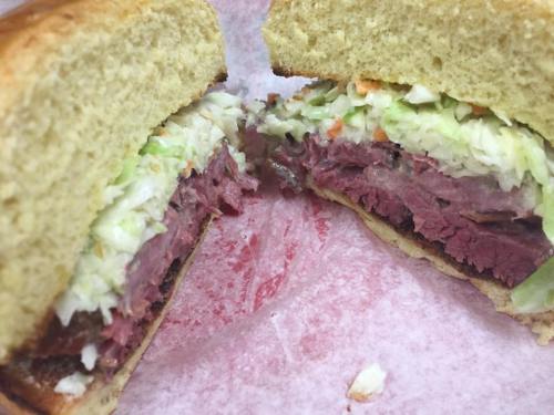 Close-up of a sandwich with layers of corned beef and coleslaw between two slices of bread.
