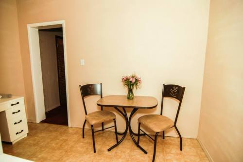 A small dining area with a round table and two chairs, featuring a vase of flowers on the table.