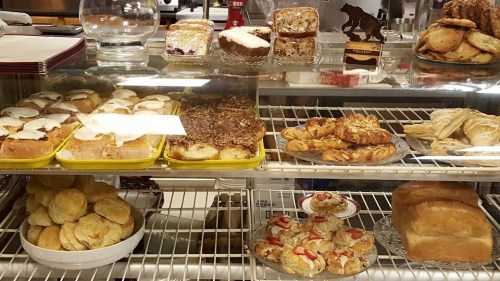 A display case filled with various baked goods, including pastries, cookies, and bread.