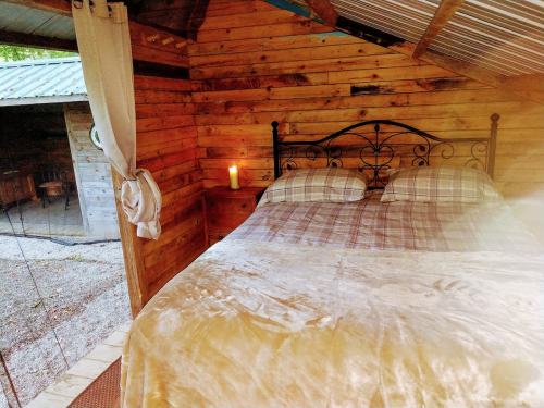 Cozy wooden cabin interior with a double bed, soft bedding, and a candle on a nightstand.