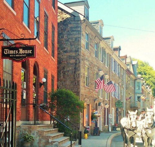 Charming street view with a bed and breakfast, historic buildings, and American flags lining the sidewalk.
