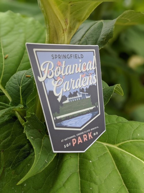 A sign for Springfield Botanical Gardens at Nathanael Greene/Close Memorial Park, surrounded by green leaves.