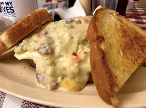 A plate with two slices of toasted bread surrounding a creamy vegetable and meat filling.