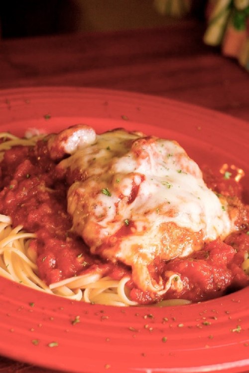 A plate of spaghetti topped with marinara sauce and melted cheese, featuring a breaded chicken cutlet.