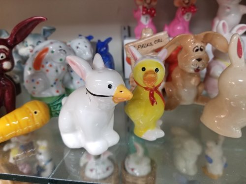 A collection of colorful ceramic animal figurines, including a white rabbit and a yellow duck, displayed on a shelf.