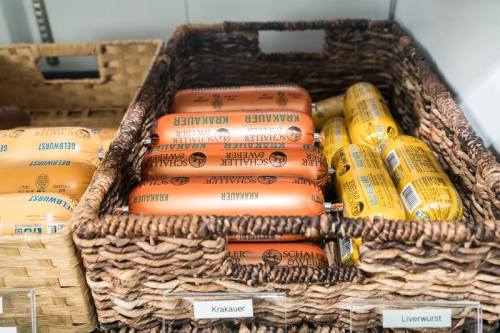 A woven basket filled with packages of Krakauer and liverwurst sausages on display.