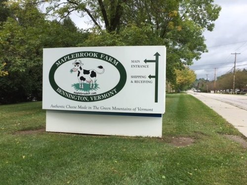 Sign for Maplebrook Farm in Bennington, Vermont, featuring a cow graphic and directions for main entrance and shipping.