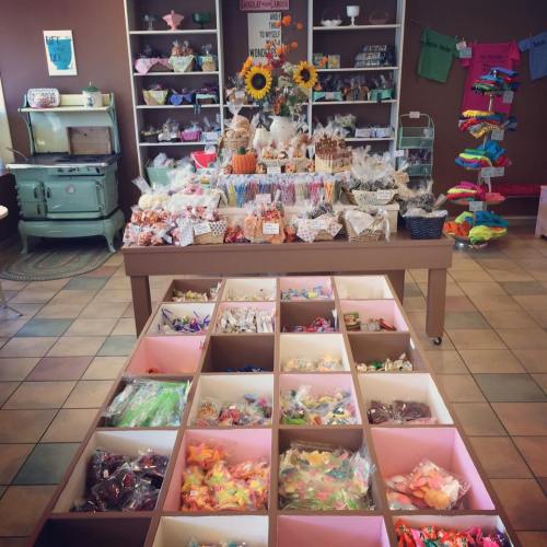 A colorful candy shop display with various sweets, treats, and decorations, featuring a central table and organized bins.