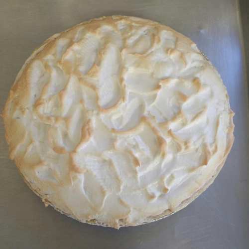 A golden-brown meringue pie with a textured, fluffy topping on a silver baking tray.