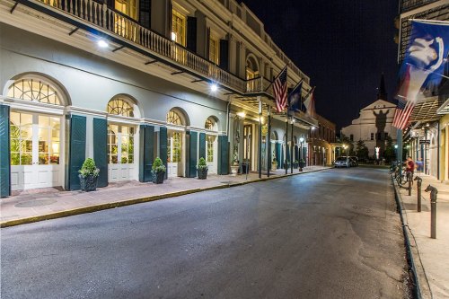 A quiet street at night, featuring historic buildings, flags, and soft lighting in a charming urban setting.