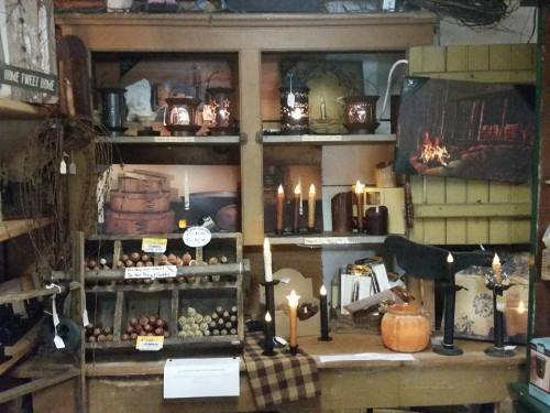 A cozy display of rustic home decor items, including candles, wooden barrels, and decorative accents on shelves.