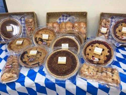 A display of various pies and baked goods on a blue and white checkered tablecloth.