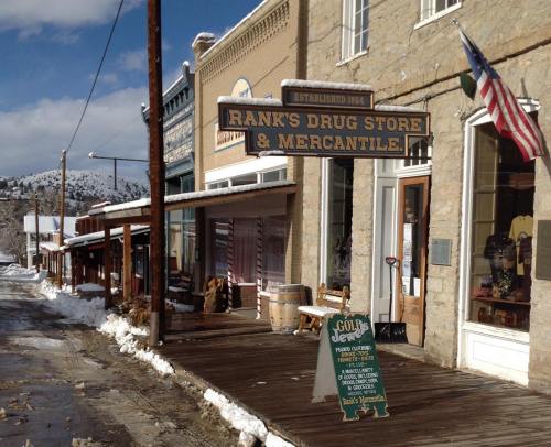 Historic Rank's Drug Store & Mercantile on a snowy street, with wooden sidewalks and a flag flying in the background.