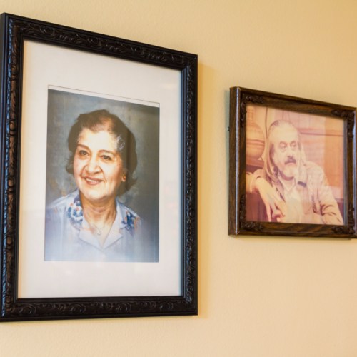 Two framed portraits on a wall: one of a smiling woman and another of a man with a thoughtful expression.