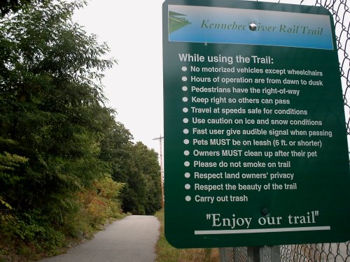 Sign on the Kennebec River Rail Trail outlining rules for trail use, including safety and pet guidelines.