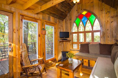 Cozy wooden interior of a cabin with stained glass windows, a rocking chair, and a small table.