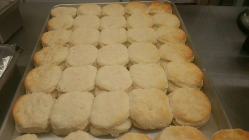 A tray of freshly baked, golden-brown biscuits arranged in neat rows.