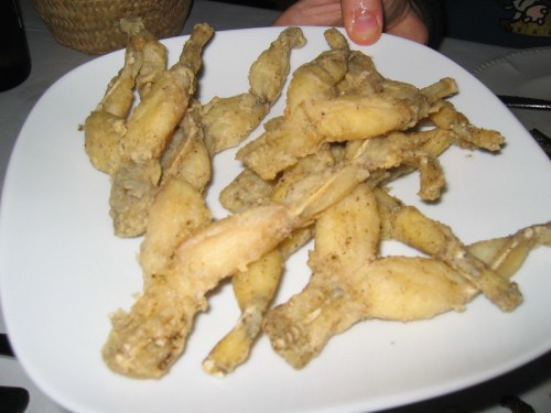 A plate of fried frog legs, golden brown and crispy, served on a white dish.